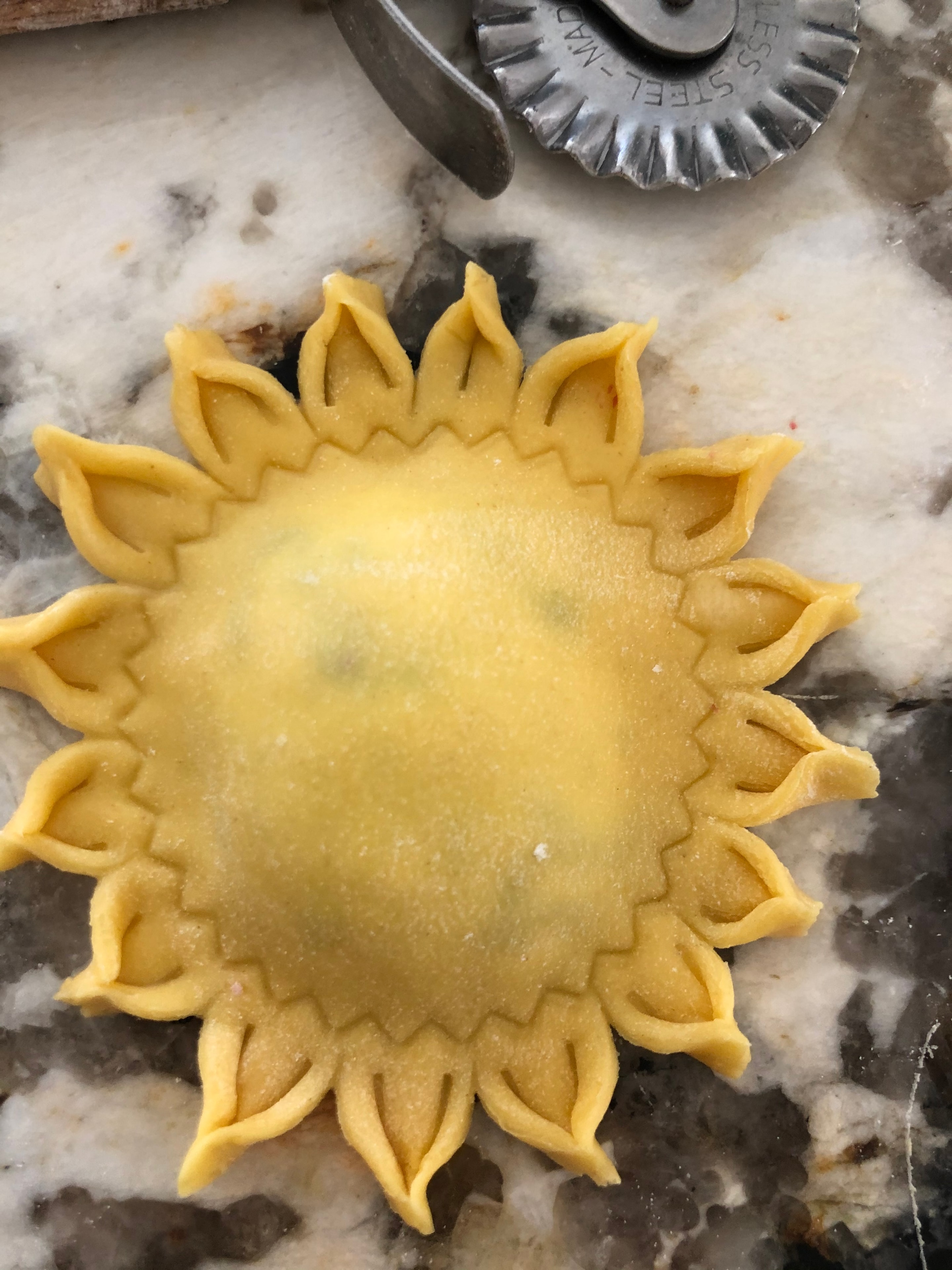 Sunflower-shaped pasta dough being cut by hand